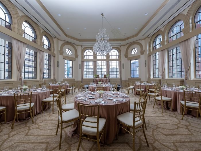 Elegantly set banquet tables and chairs under chandeliers in Tip Top Tap South at Warwick Allerton Chicago