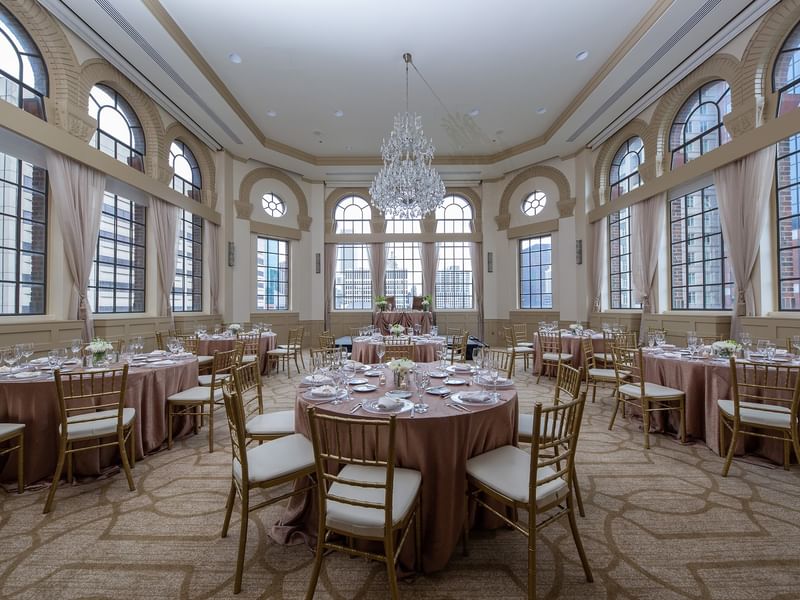 Elegantly set banquet tables and chairs under chandeliers in Tip Top Tap South at Warwick Allerton Chicago