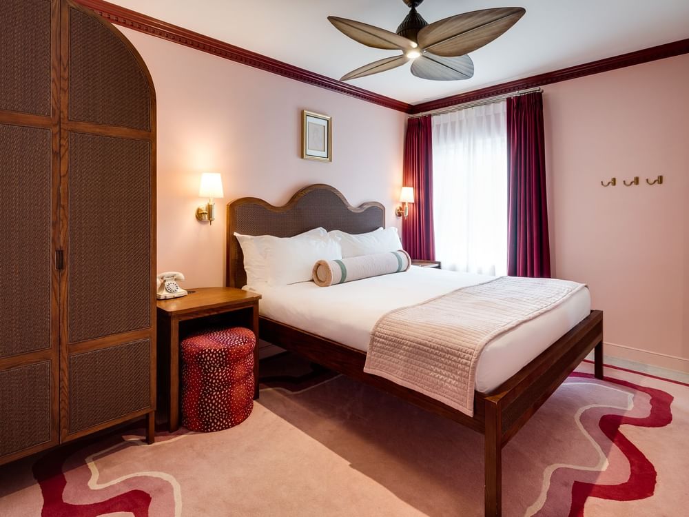 A wide view of a hotel room with a king-sized bed, nightstand, and closet
