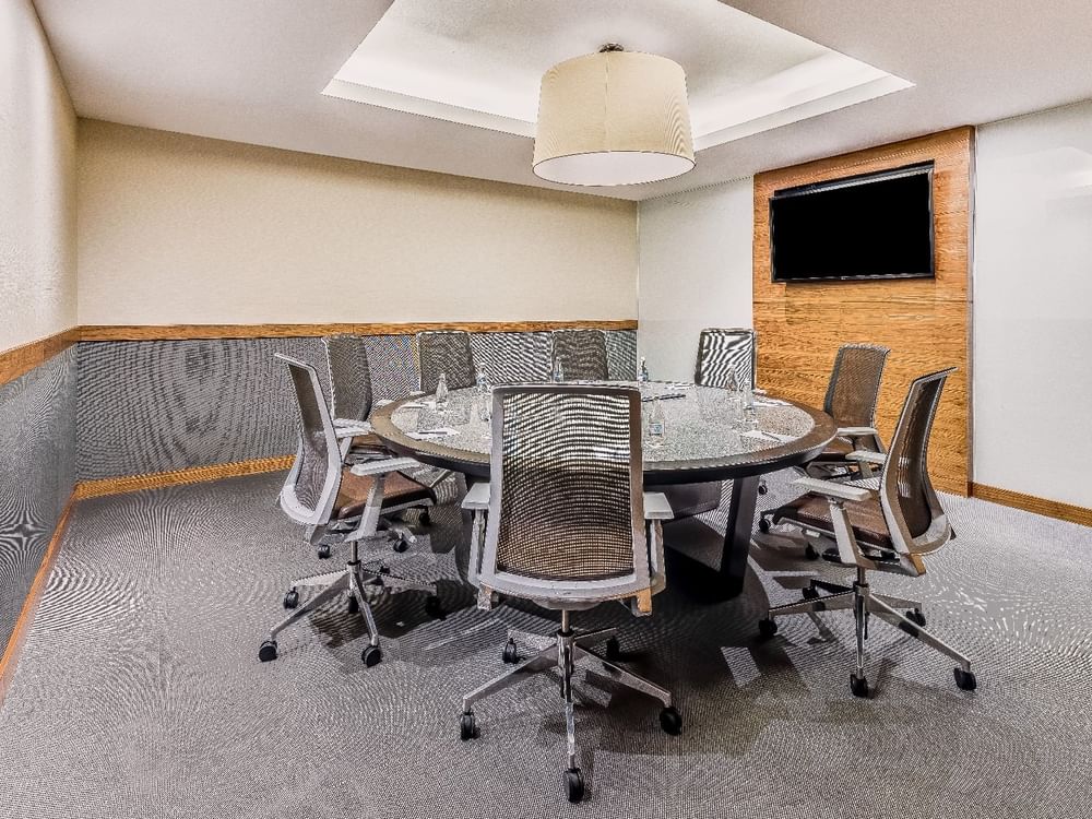 Round meeting room table with office chairs & a TV at Live Aqua Resorts and Residence Club