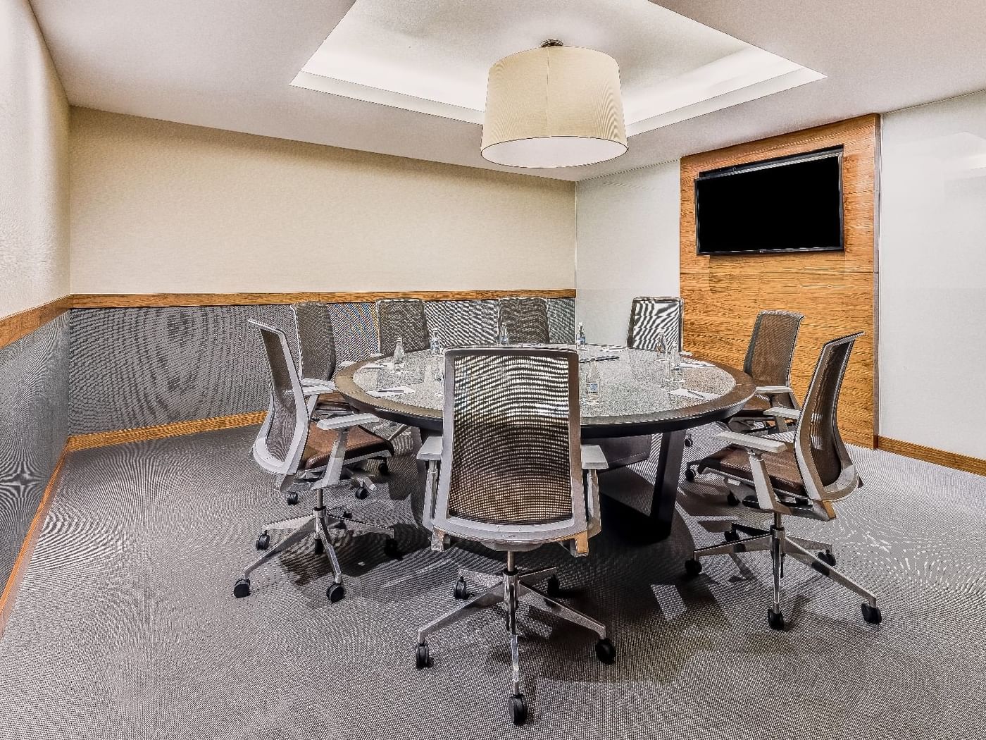 Round meeting room table with office chairs & a TV at Live Aqua Resorts and Residence Club