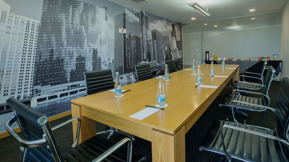 Boardroom setup with notepad and water bottle near buffet table with city views in the business center at Real Inn Mexicali