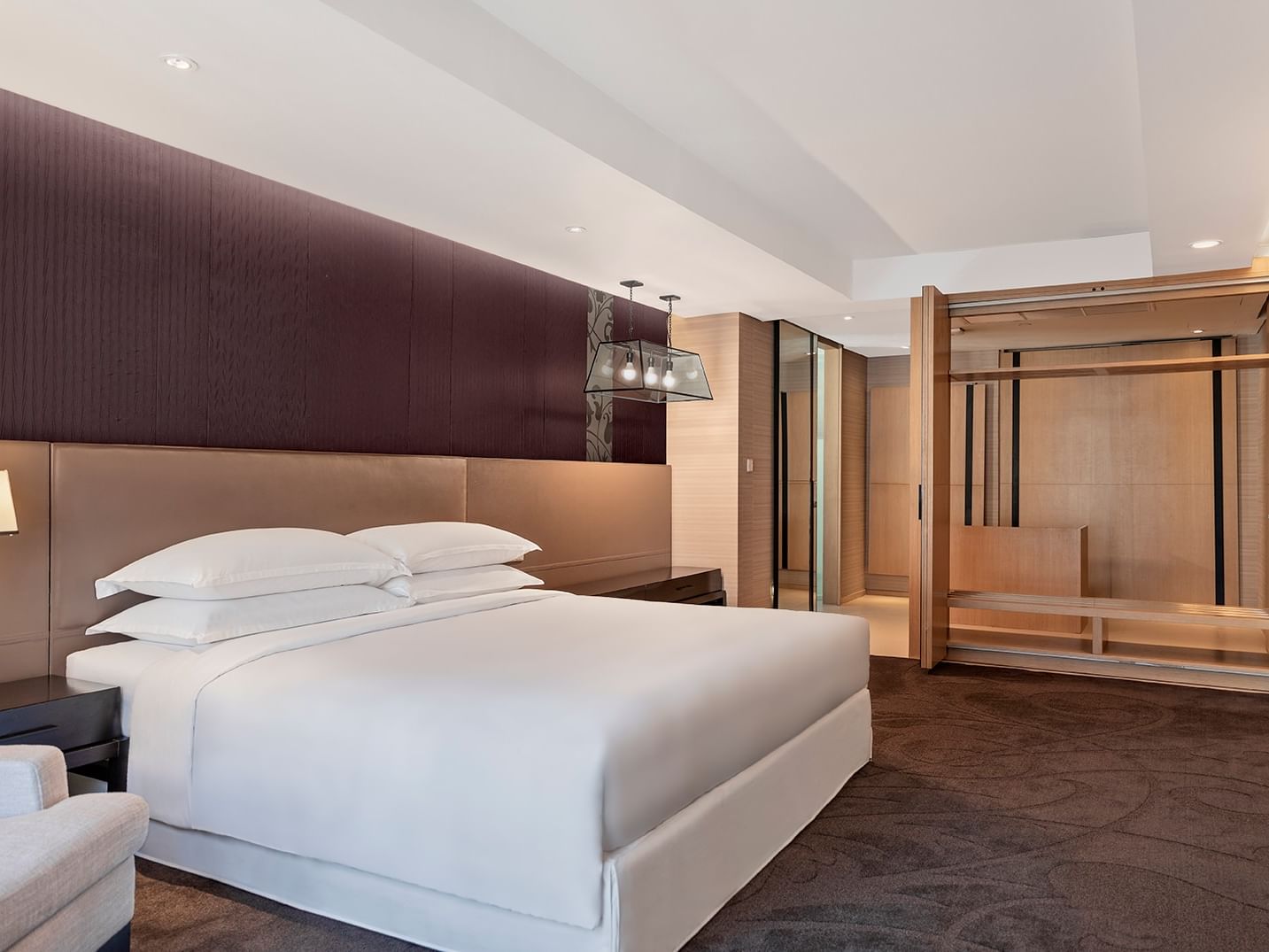 Presidential Suite at Paradox Bangkok Sukhumvit with a bed by an open closet under a hanging light, featuring Bangkok suites