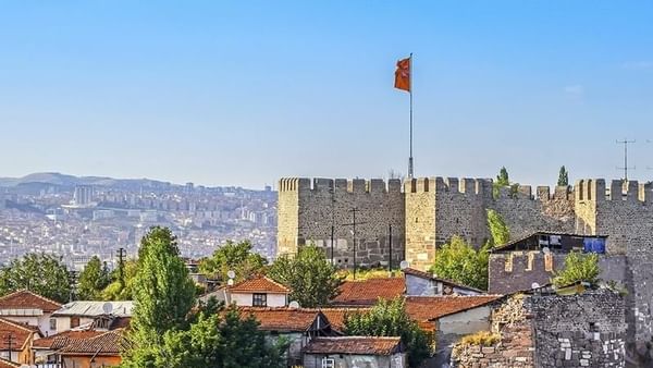 Ankara Castle walls by red-roofed houses surrounding a tall flag pole near Warwick Ankara