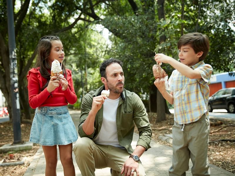 Father & children enjoying ice cream on a path with lush greenery at Grand Fiesta Americana