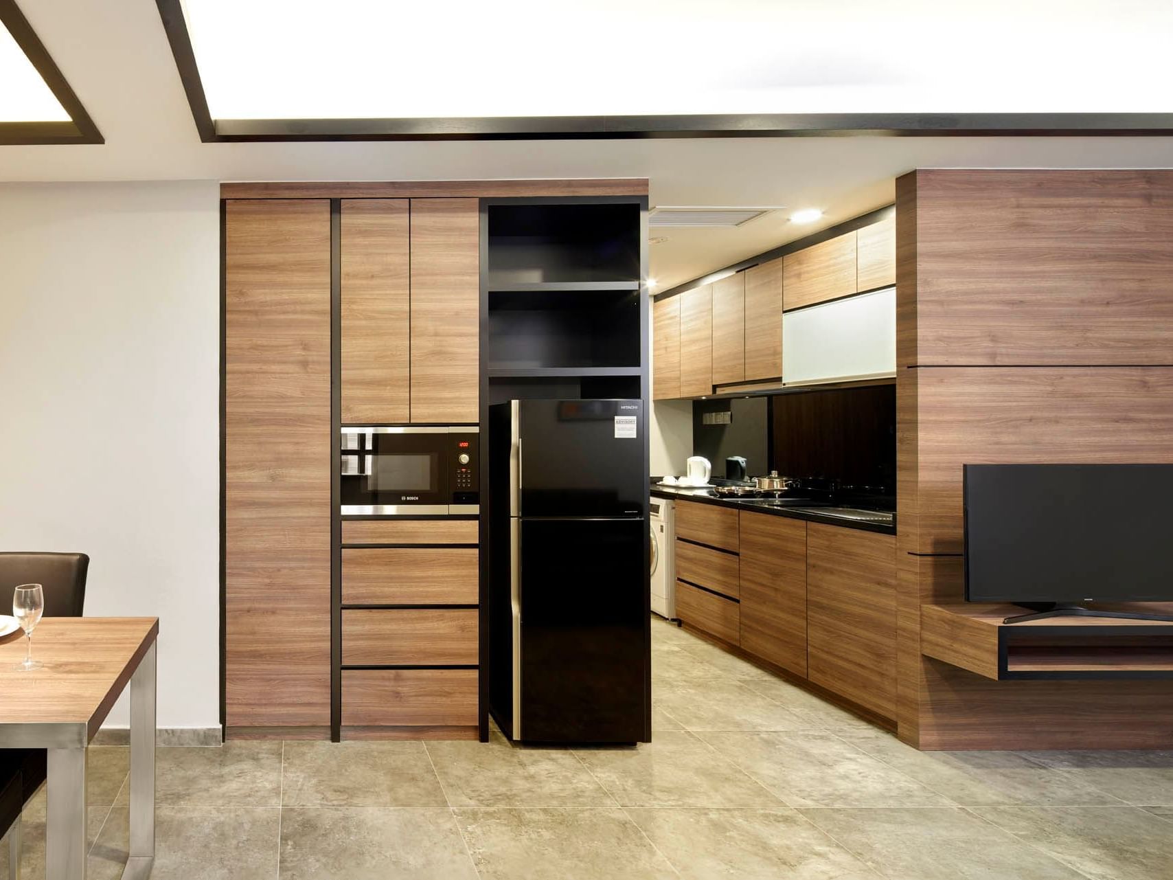 Image 74: Modern Two Bedroom kitchen with wooden cabinets, black appliances, and a TV on grey flooring at Orchard Grand Court
