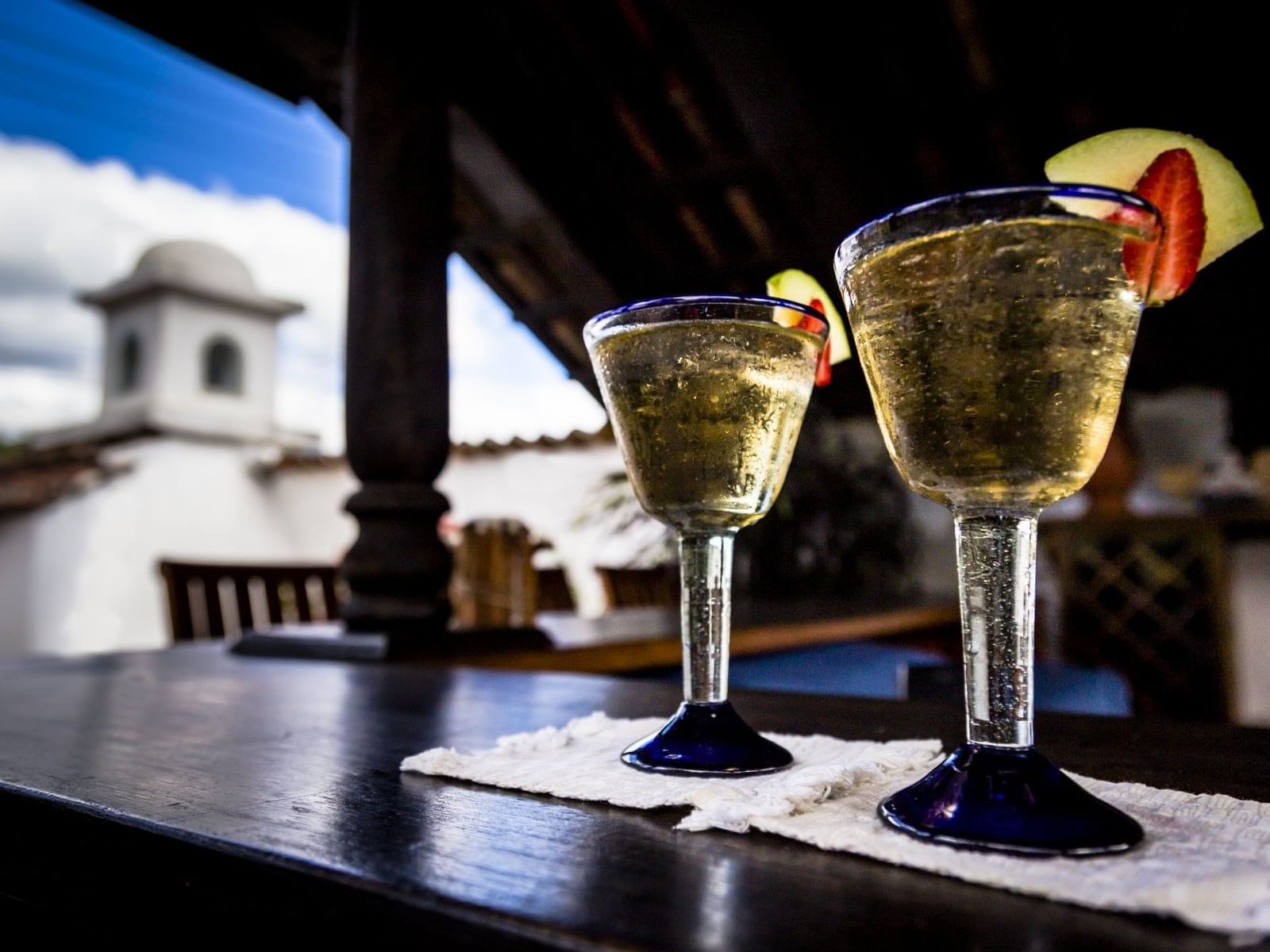 Two glasses of golden cocktails garnished with fruit served in Roof Top Terrace at Porta Hotels