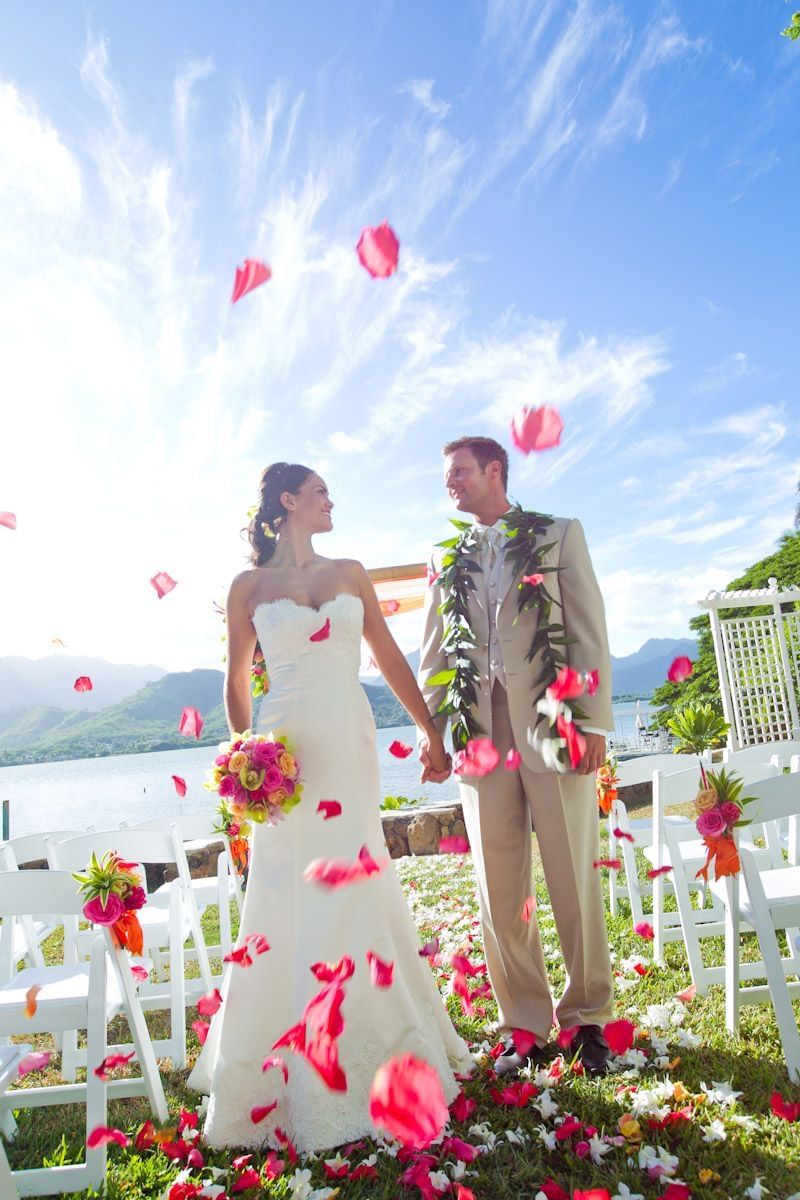 Bride & groom posing with a rain of flower petals outdoors at Paradise Bay Resort