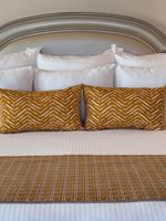 Corner King features White bed with yellow pillows by a silver headboard under soft light at Warwick Melrose Dallas