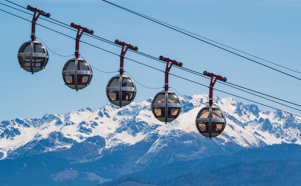 Spherical cable cars of the Grenoble Bastille cable car over snowy peaks near ResidHotel Grenoble Grenette