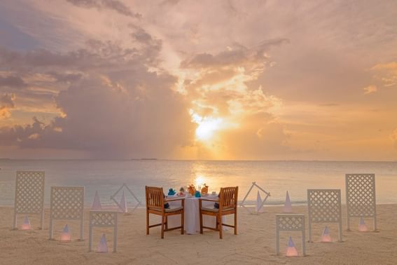 A beach setting for a romantic dinner at sunset, with a table near Grand Park Kodhipparu, Maldives