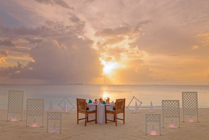 A beach setting for a romantic dinner at sunset, with a table near Grand Park Kodhipparu, Maldives