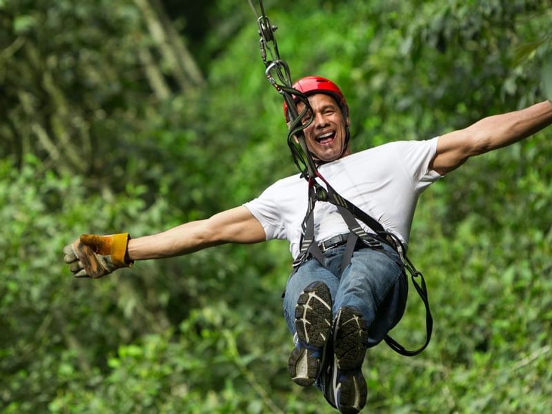 Man ziplining through a forest near Fiesta Americana Travelty