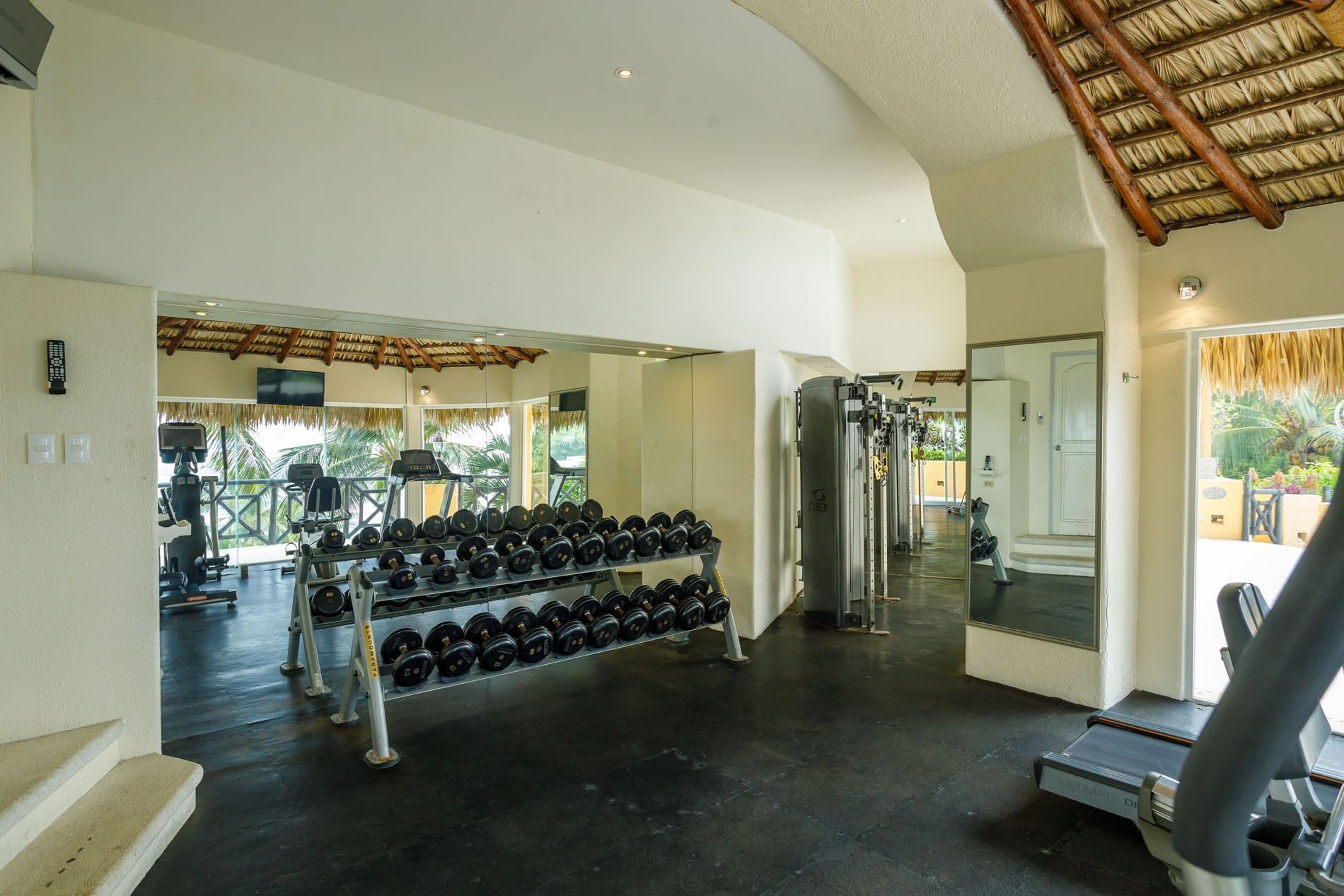 Weight room featuring a rack of dumbbells, large mirrors, and tropical garden views at Quinta Real Acapulco