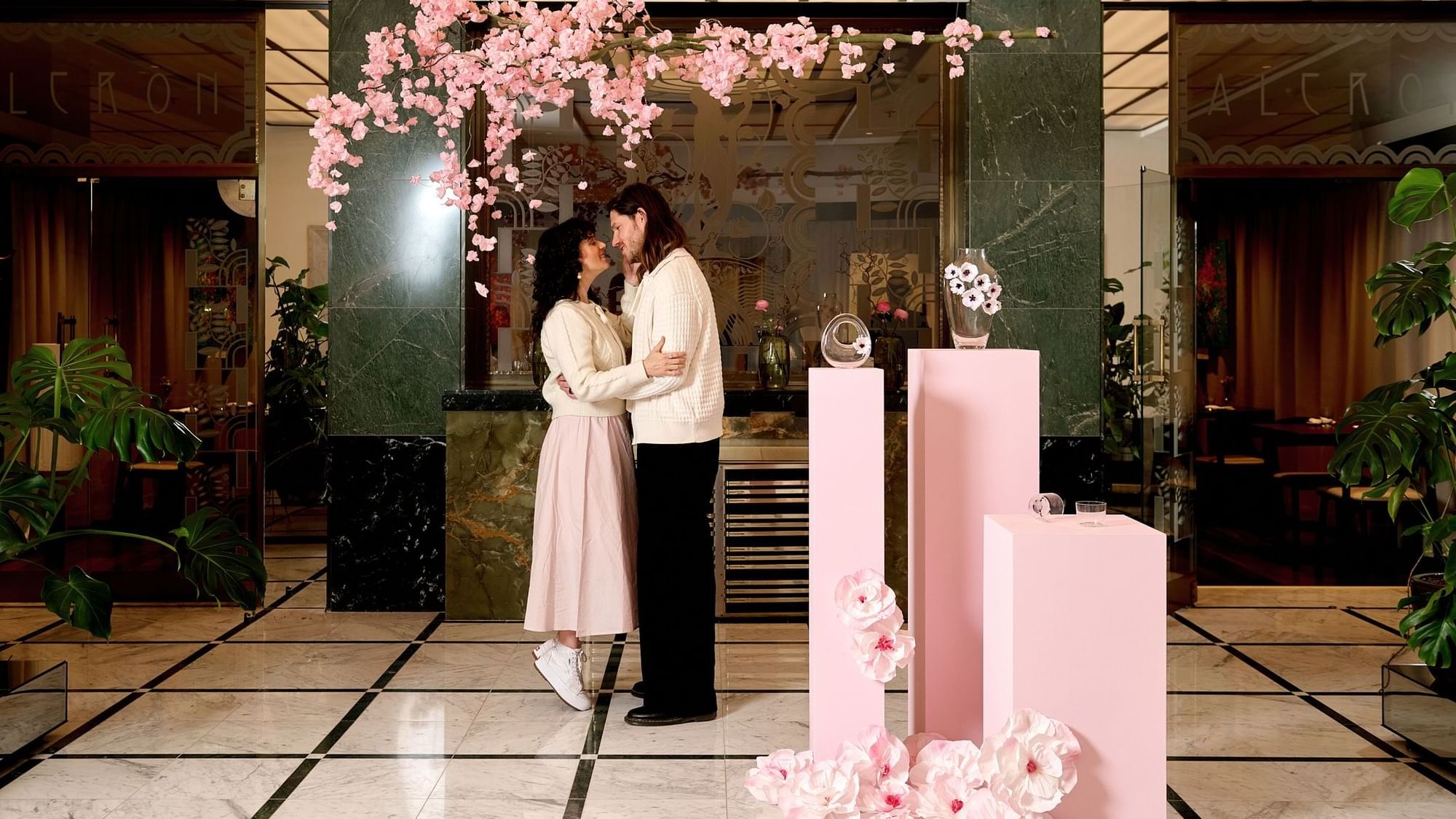 Couple posing in the indoor setting featuring a beautiful floral arrangement and elegant decor at Almanac X Alcron Prague