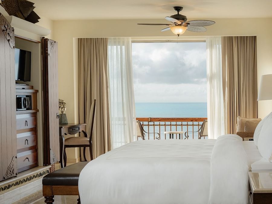 Double bed with a TV and a balcony area in Junior Suite Ocean View at Marquis Los Cabos Resort
