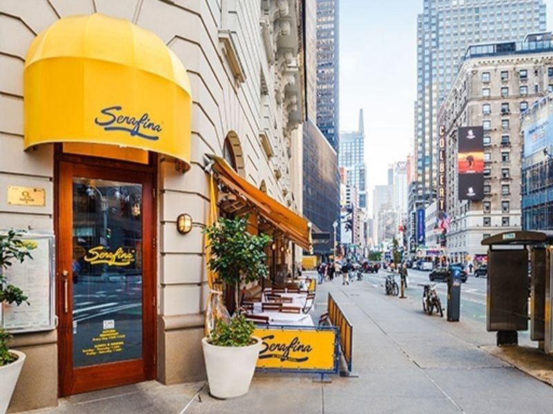 A restaurant exterior with a yellow awning and glass door on a city street.