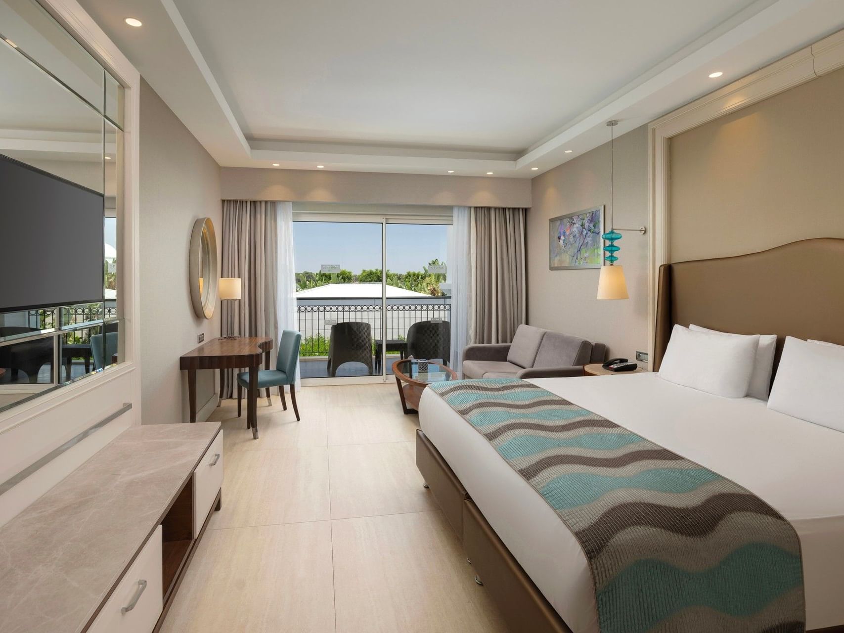 Spacious hotel room with king bed, balcony view, seating area, and modern amenities at Titanic Deluxe Golf Belek