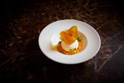 Gourmet white chocolate mousse dessert served with diced mango on a dark marble table at The May Fair Hotel