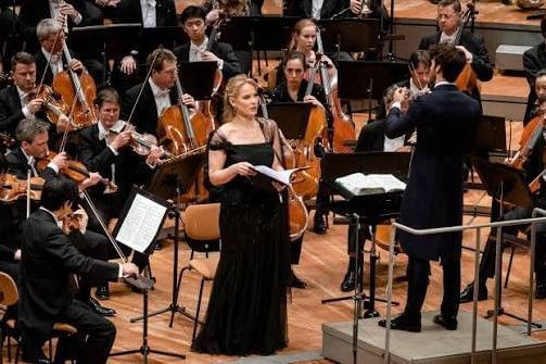 Opera singer during a classical concert with orchestra, conductor and elegant stage atmosphere