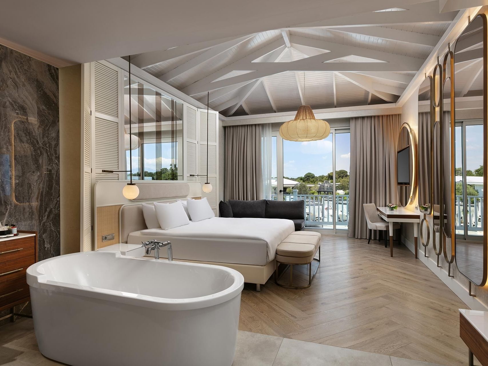 Spacious hotel suite with king bed, freestanding bathtub, modern furnishings, and balcony access at Titanic Deluxe Golf Belek