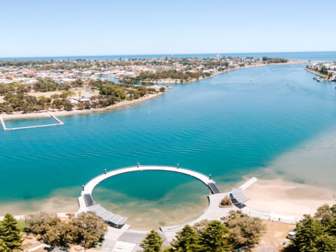 Aerial view of a vibrant blue Ocean featuring Kwillena Gabi Pool and modern buildings near The Sebel Mandurah