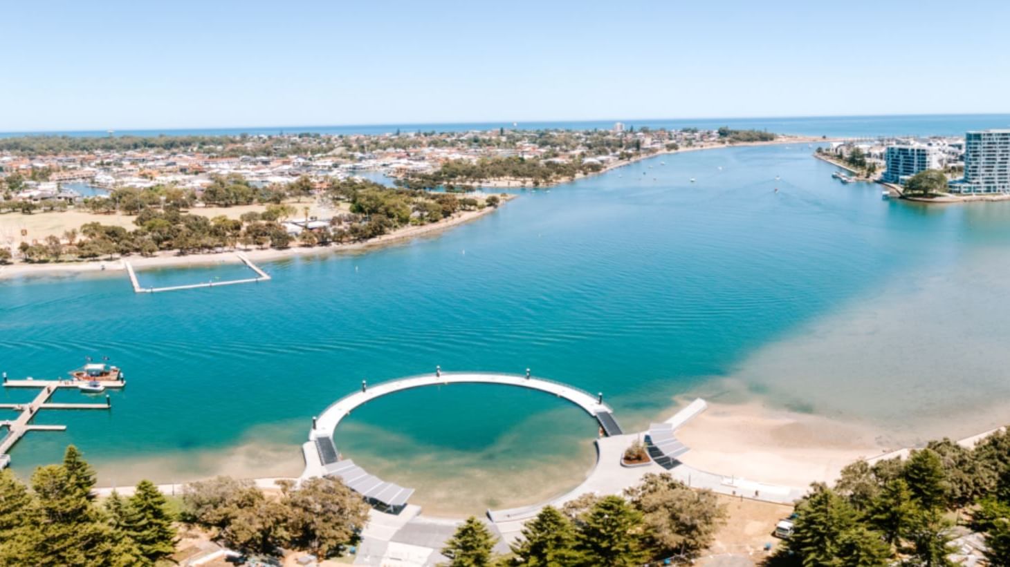 Aerial view of a vibrant blue Ocean featuring Kwillena Gabi Pool and modern buildings near The Sebel Mandurah