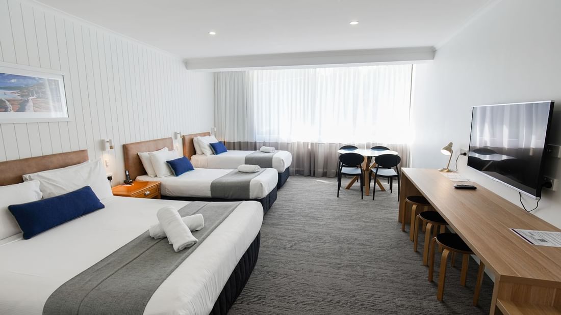 King bed and twin single beds arranged by the dining table in Mercure Charlestown