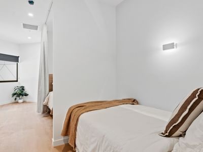 Cozy bedroom with white walls, wooden floors, and simple decor at UniLodge Brisbane City.