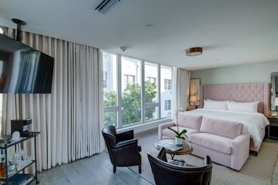 room with large bed, love seat and chairs with floor to ceiling 