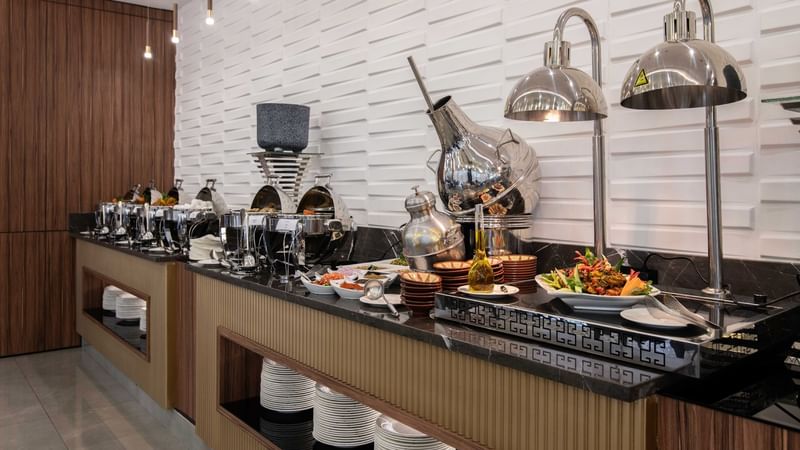 A modern buffet display featuring shiny chafing dishes at Warwick Hotels and Resorts