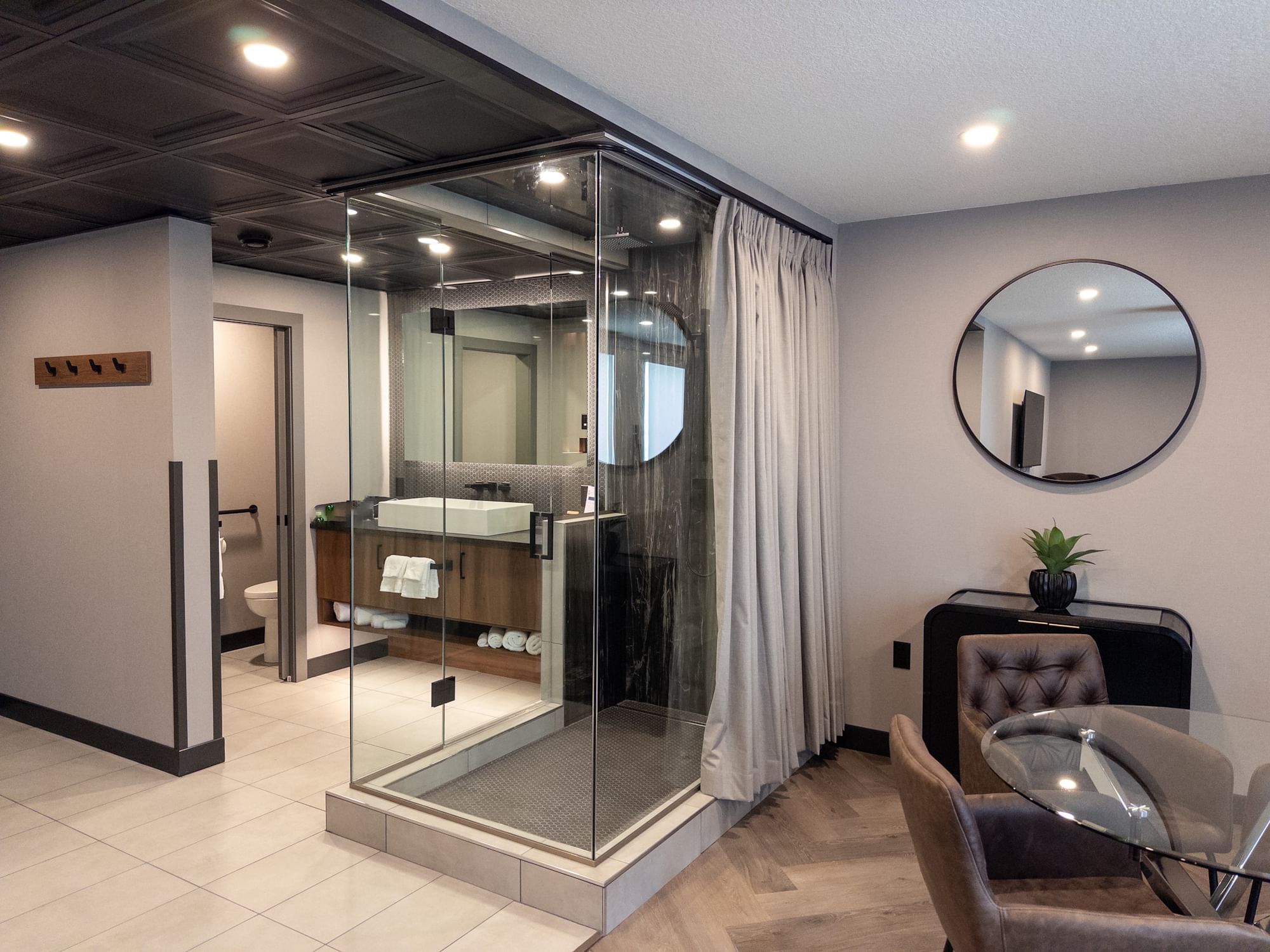 Elegant Premier Suite bathroom with glass shower, vanity, and dining area at Carriage House Hotel & Conference Centre, Calgary.