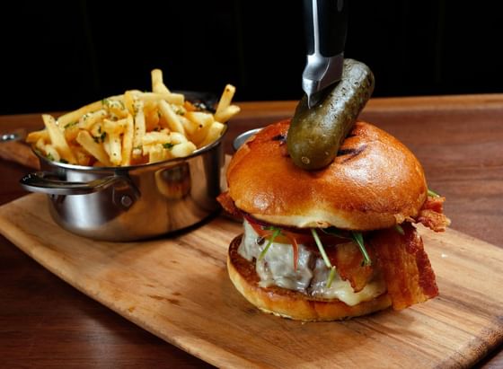 Burger, pickle & crispy fries served in Tony's at J House Greenwich, a modern boutique hotel in Greenwich Connecticut