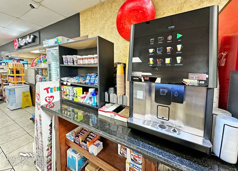 A convenience store with a coffee machine and snack shelf