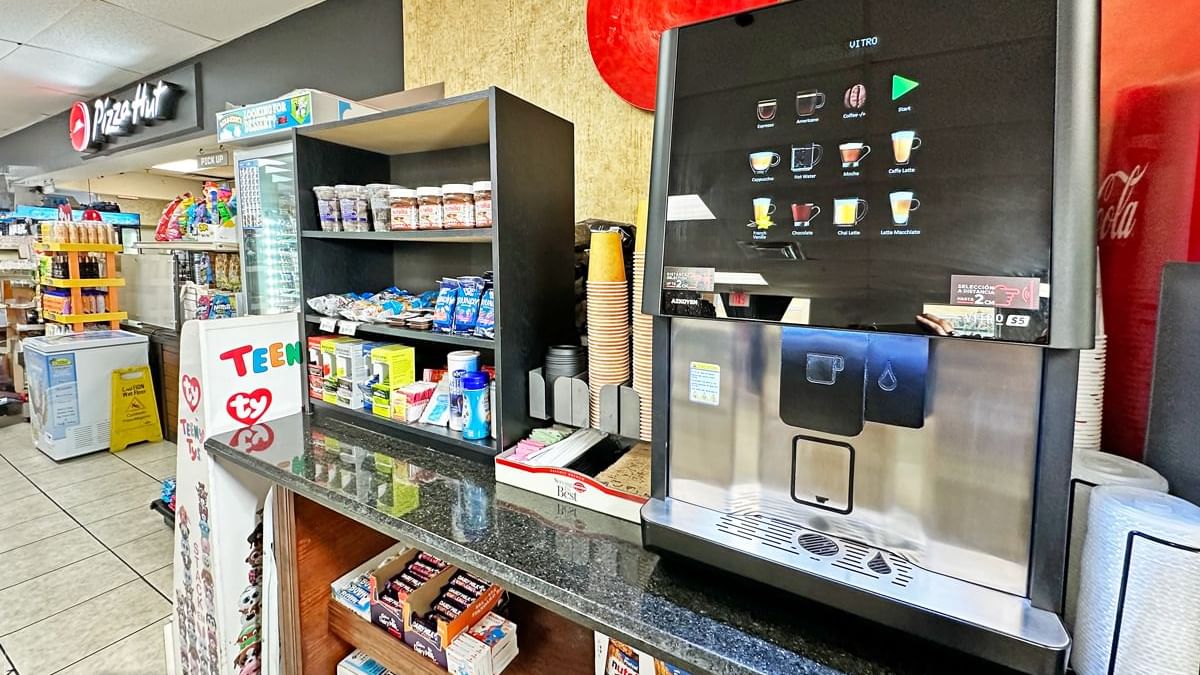 A convenience store with a coffee machine, soda, and snacks.