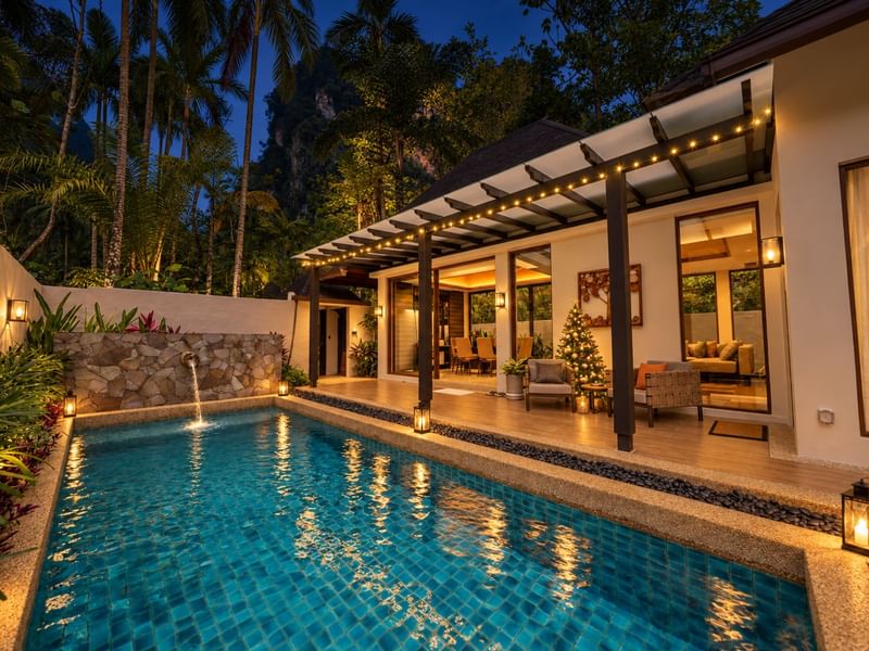 Illuminated private pool villa with tropical landscaping and festive Christmas tree indoors at dusk at The Banjaran Hotsprings Retreat promoting festive year end stay