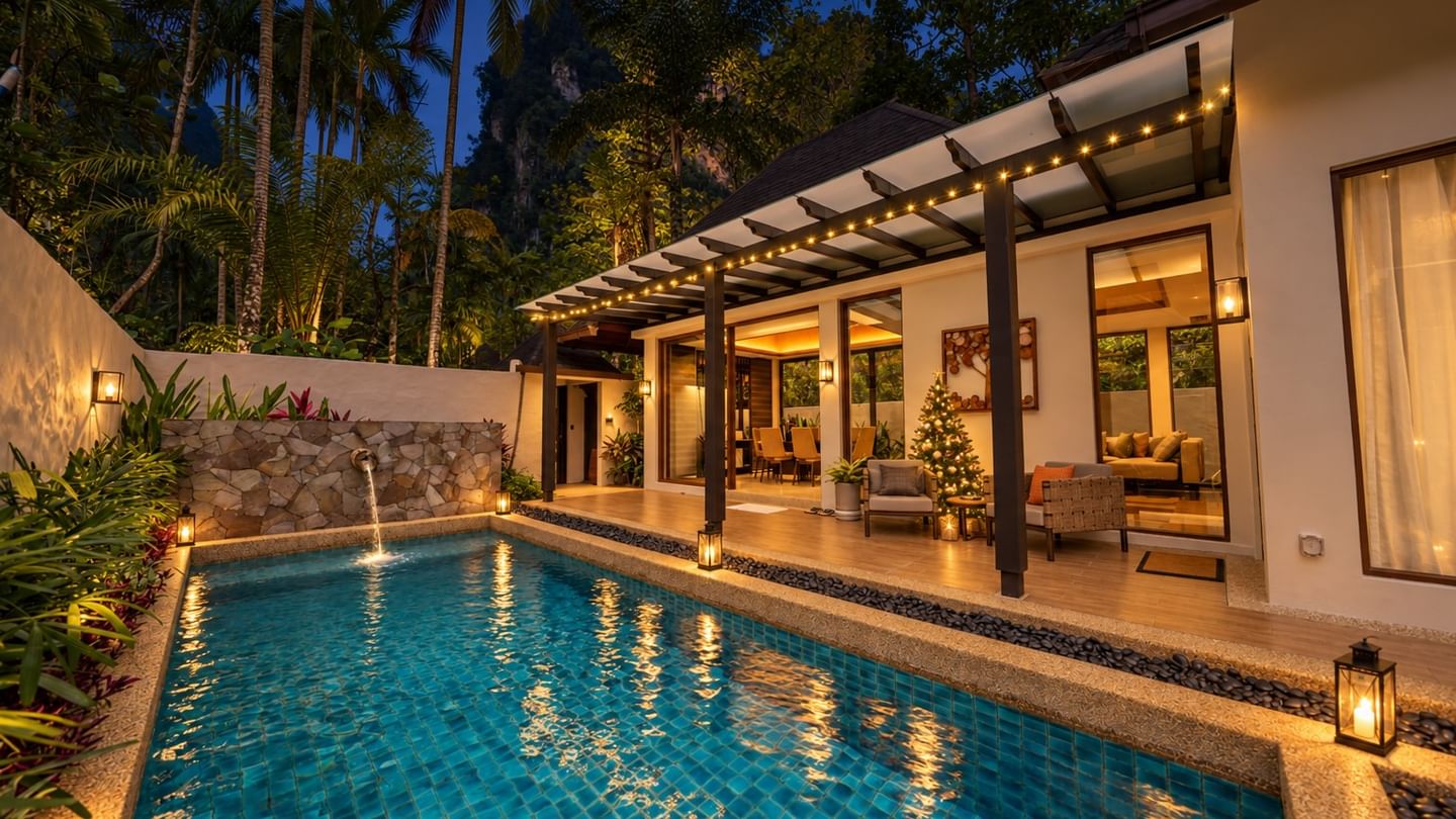Illuminated private pool villa with tropical landscaping and festive Christmas tree indoors at dusk at The Banjaran Hotsprings Retreat promoting festive year end stay