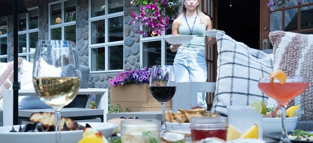 An outdoor table at a restaurant in Canmore with cocktails, oysters, mussels, and other happy hour dishes.