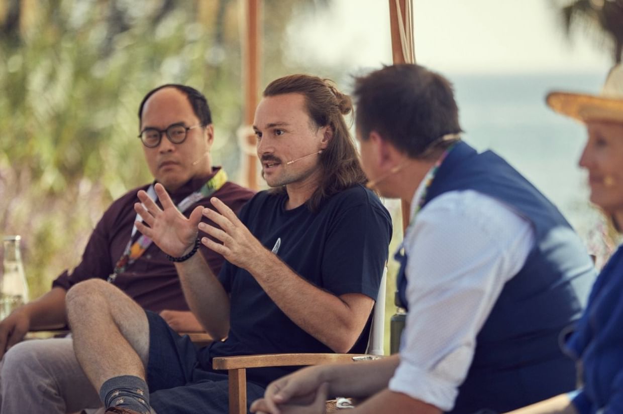 Outdoor panel discussion with a man gesturing mid-sentence toward someone off-camera at Marbella Club resort