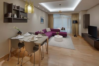 spacious living room with square dining table and maroon sofa