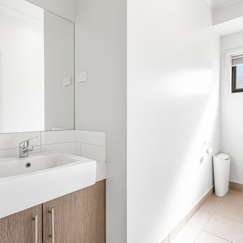Clean and modern bathroom with white sink, mirror, toilet, and tiled floors.