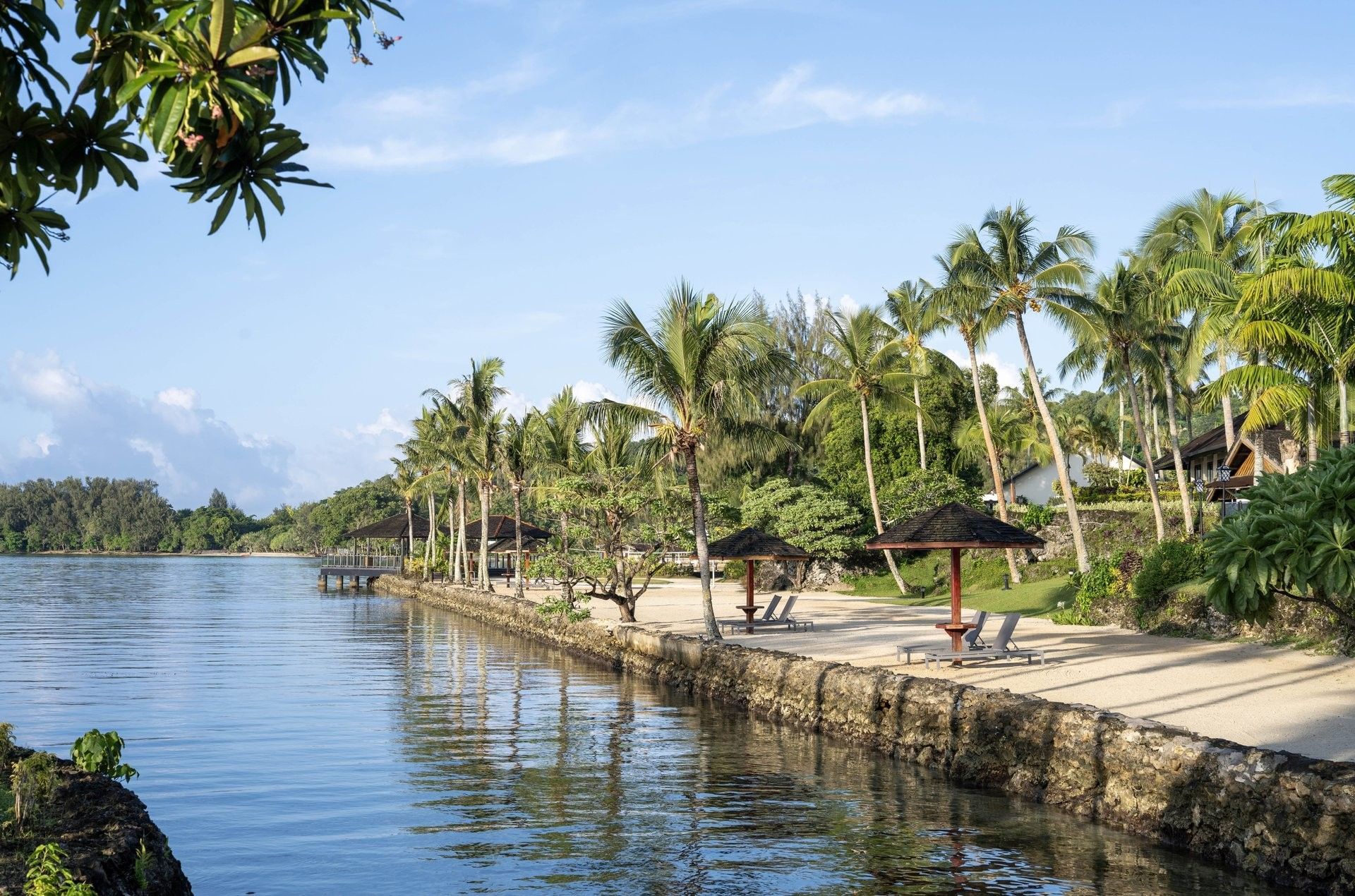 Tropical beach view with palm trees and lounge chairs at Warwick Le Lagon - Vanuatu
