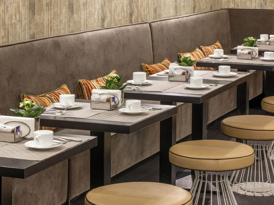 Dining area with tables, white cups, and cushions against a textured wall, showcasing a cozy ambiance at The Republic Hotel