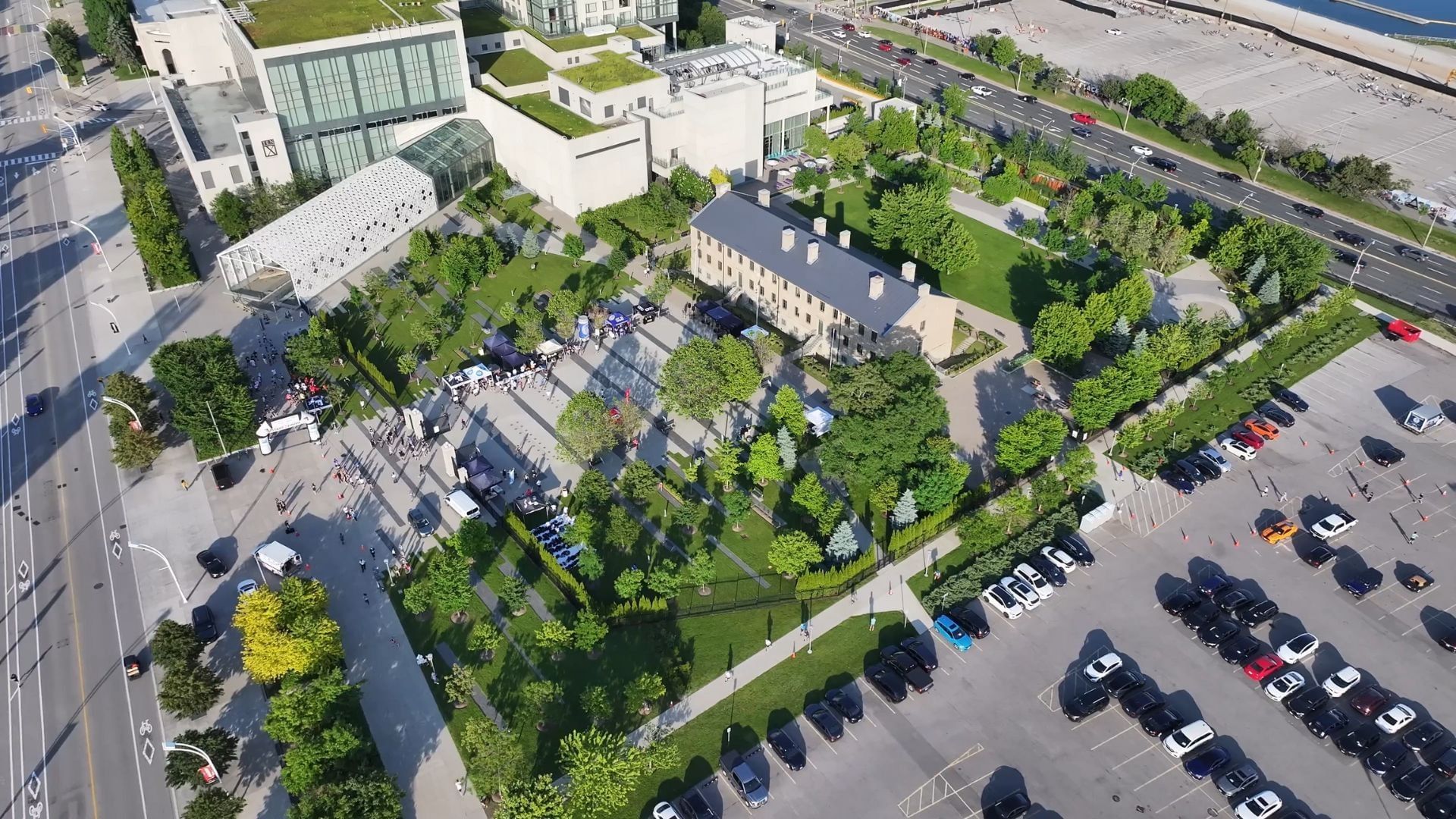 Aerial view of a historic barracks building by a parking lot, surrounded by trees and pathways near Hotel X Toronto