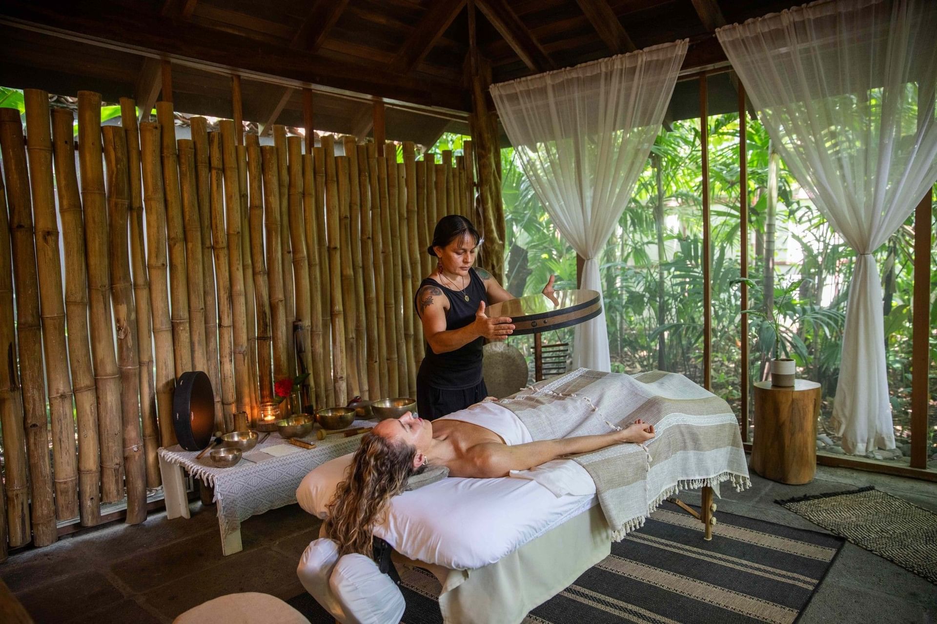 Sound healing session in Lahari Wellness Center using a frame drum over a guest at Cala Luna Boutique Hotel