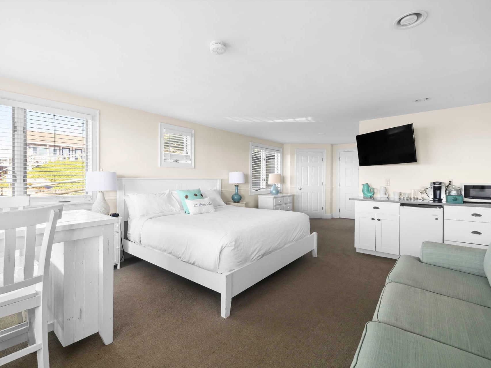 Bed and kitchenette with arranged seating in Suntide Oceanfront King at Chatham Tides Resort