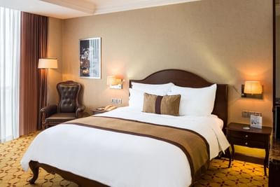 Club Deluxe Room with a king sized bed & a comfy chair at Eastin Grand Hotel Saigon