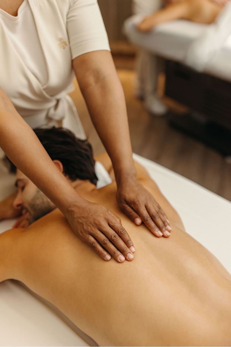 Therapist performing a back massage on a male guest lying face down on a massage table at Hotel X Toronto