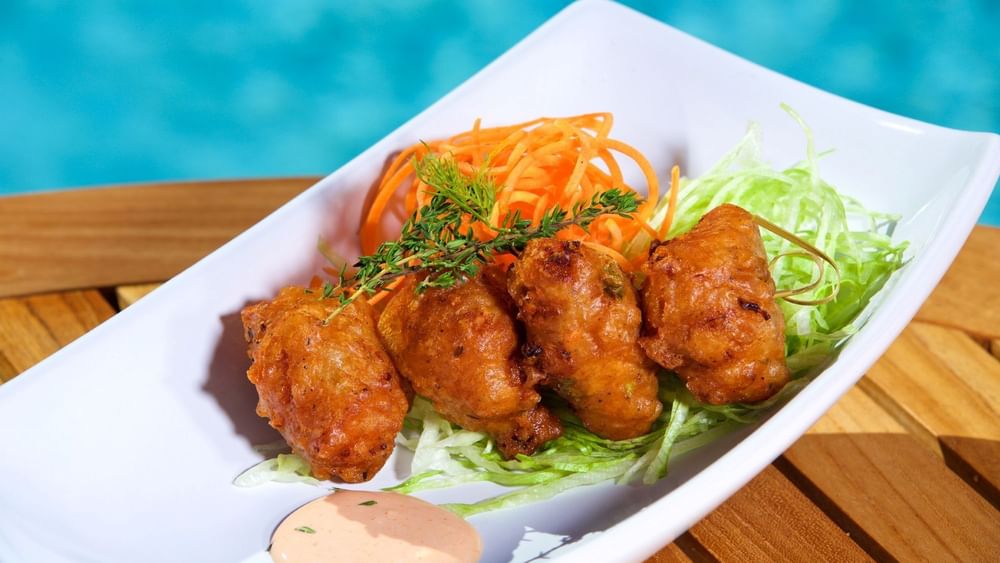 Crispy fritters with a sauce under a herb sprig in Chickcharnie's Pizzeria & Grille at Warwick Paradise Island Bahamas