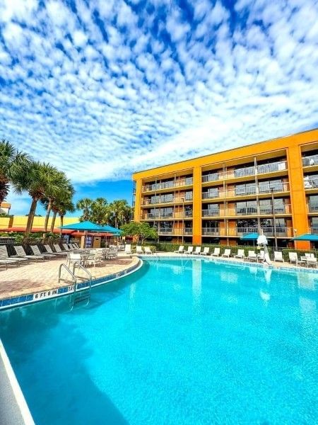 A sparkling swimming pool beneath a blue sky at Rosen Inn Lake Buena Vista, a family-friendly hotel in Orlando.